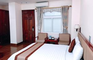 a bedroom with a bed and two chairs and a window at Paradis Hotel in Ha Long