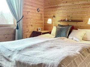Holiday home Holmsjö III في هولمسيو: غرفة نوم بسرير وجدار خشبي