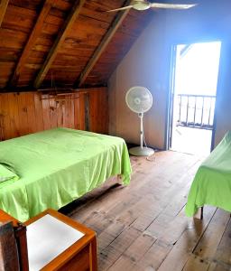 a bedroom with a green bed and a fan at Nexpa cabañas Martha surf spot in Caleta de Campos