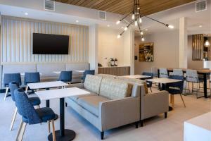 a waiting room with a couch and tables and a tv at TownePlace Suites by Marriott Canton Riverstone Parkway in Canton