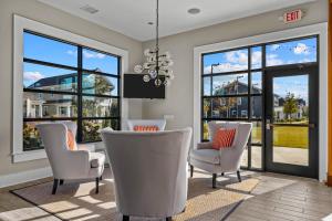 una sala de estar con sillas blancas y ventanas grandes. en Southern Glow, en Beaufort