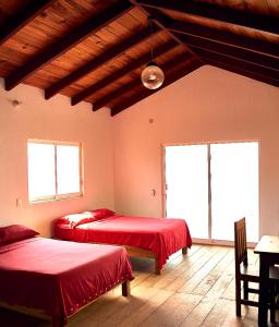 a room with two beds and a table and two windows at Nexpa cabañas Martha surf spot in Caleta de Campos