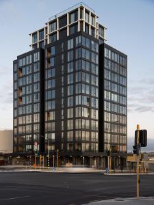 um edifício de escritórios preto alto numa rua da cidade em Stay Max Apartment for Perfect Short Stay em Auckland