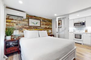 キーウェストにあるJulia Whitehead Guest Suitesの白いベッドとレンガの壁が備わるベッドルーム1室が備わります。