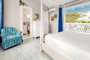 Julia Whitehead Guest Suites في كي ويست: غرفة نوم بسرير وكرسي ونافذة