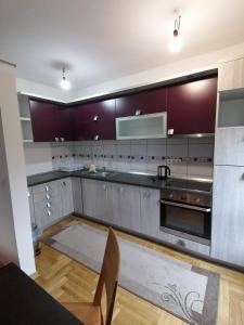 una cocina con electrodomésticos de acero inoxidable y armarios púrpuras en Delux Apartment, en Sarajevo