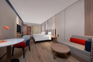 um quarto de hotel com uma cama e um sofá em Holiday Inn Express Shanghai Pujiang, an IHG Hotel em Xangai