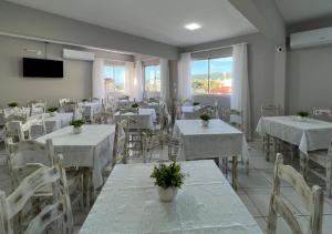 un comedor con mesas blancas y sillas blancas en Ilha Forte Praia Hotel, en Florianópolis