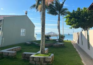 un edificio blanco con bancos y palmeras junto al océano en Ilha Forte Praia Hotel, en Florianópolis