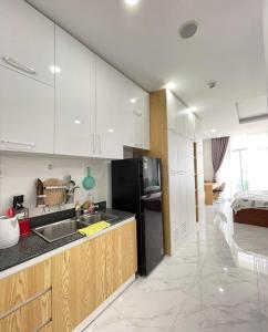 eine Küche mit weißen Schränken und einem schwarzen Kühlschrank in der Unterkunft Ocean Vista - Sealinks in Ấp Chợ Dinh