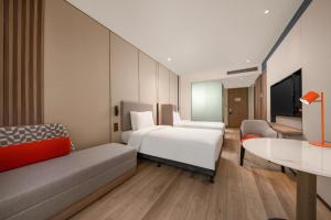 Holiday Inn Express Shanghai Pujiang, an IHG Hotel في شانغهاي: غرفه فندقيه بسرير واريكه