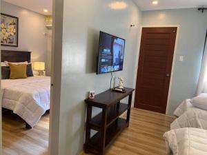 ein Schlafzimmer mit einem Bett und einem TV an der Wand in der Unterkunft The Great Molave FAMILY ROOM in Cavite
