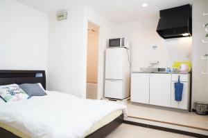 a bedroom with a white bed and a refrigerator at 難波南52 in Osaka