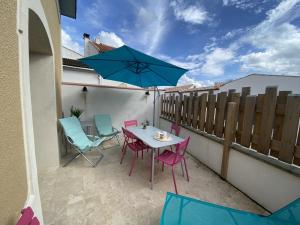 un patio con mesa, sillas y sombrilla azul en Maison Fouras, 3 pièces, 5 personnes - FR-1-709-34, en Fouras