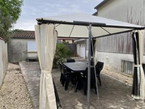 un tavolo nero e sedie sotto un ombrellone bianco di Maison Fouras, 3 pièces, 5 personnes - FR-1-709-43 a Fouras
