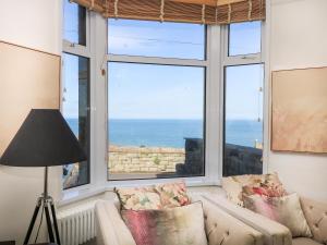 a living room with a couch and a large window at Porthmeor Beach House in St Ives