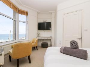 a bedroom with a bed and a desk and a television at Porthmeor Beach House in St Ives