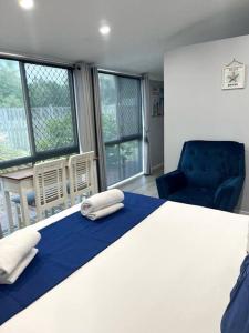 1 dormitorio con 1 cama, 1 silla y ventanas en The Villas - Hervey Bay - 2 separate villas, en Urangan