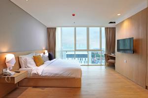 a hotel room with a bed and a television at Midtown Residence Surabaya in Surabaya