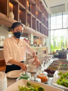 een vrouw met een masker in een keuken die eten klaarmaakt bij Ra Suites Simatupang in Jakarta