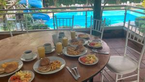 uma mesa com pratos de comida e uma piscina em Hotel El Broche em Yopal