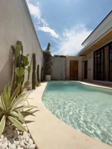 a swimming pool next to a house with a cactus at Emma’s Villa in Seminyak
