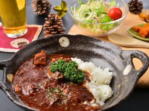 a pan filled with meat and rice and a salad at Kurumayama Kogen Guesthouse Urara in Chino