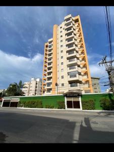un gran edificio blanco con una fachada verde junto a una calle en Guarujá enseada sp, en Guarujá