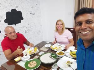 Enara Luxury Stay في Katugastota: مجموعة من الناس يجلسون على طاولة يأكلون الطعام