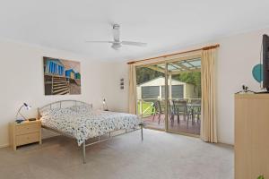 a bedroom with a bed and a balcony with a table at Dolphin Drift 29 Dolphin Avenue in Carrickalinga
