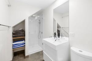 a white bathroom with a sink and a shower at A home amongst the gum trees in Torquay