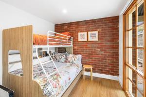 Schlafzimmer mit Etagenbett und Ziegelwand in der Unterkunft A home amongst the gum trees in Torquay