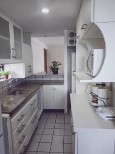 una cocina con armarios blancos y fregadero en BOA VIAGEM 2 quartos 100 m da praia até 5 pessoas, en Recife