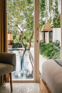 a bedroom with a view of a pool through a window at Umpadhi Canggu in Canggu