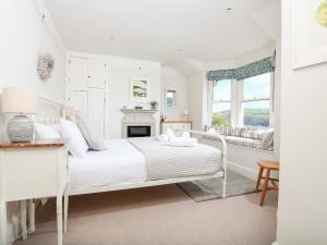 a white bedroom with a bed and a fireplace at Juniper Cottage in Dartmouth