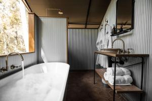 a bathroom with a tub and a sink and a mirror at Paperbark Camp in Woollamia
