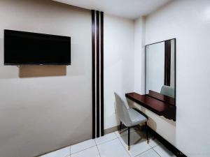 Pokój hotelowy z biurkiem i telewizorem na ścianie w obiekcie Bamboo Garden Bussiness Inn w mieście Dipolog