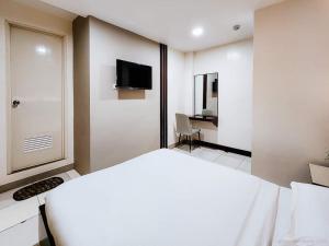 a white room with a bed and a tv on the wall at Bamboo Garden Bussiness Inn in Dipolog
