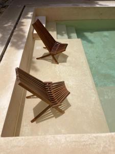 - deux chaises en bois installées à côté de la piscine dans l'établissement Casa Aurora Mérida, Centro Histórico, à Mérida