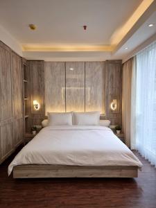 a bedroom with a large white bed with wooden walls at New! Luxury Landmark Residence Apartment 2+1BR 96m in Bandung