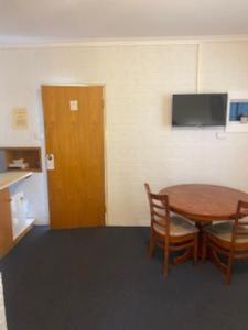 a room with a table and chairs and a television at Kinross Inn in Cooma