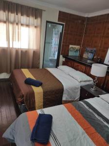 Habitación de hotel con 2 camas y espejo en CASA MUY CONFORTABLE EN ZAMORA CHINCHIPE incluye desayuno, en Zamora