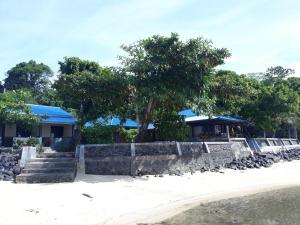 a resort with a stone retaining wall and trees at Bunaken Sunrise Beach in Manado