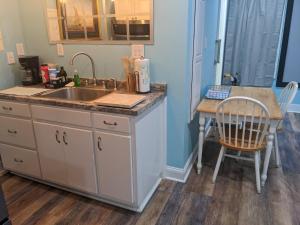 a kitchen with a sink and a table with a chair at Cozy studio with movie theater, beach 5 min away in Morehead City