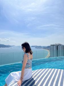 uma mulher sentada à beira de uma piscina em Sea Moon Cam Ranh Beach House em Cam Ranh