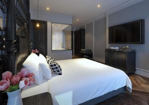 a bedroom with a large white bed and a flat screen tv at Le Grand Hanoi Hotel - 18 Hàng Quạt by Bay Luxury in Hanoi