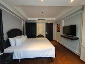 a bedroom with a white bed and a flat screen tv at Le Grand Hanoi Hotel - 18 Hàng Quạt by Bay Luxury in Hanoi