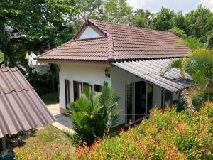 Casa blanca pequeña con techo de baldosa en Vacation House with tropical garden and private pool, en Rayong
