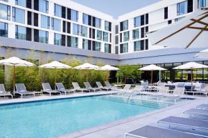 a swimming pool with chairs and umbrellas next to a building at Residence Inn By Marriott Dallas By The Galleria in Dallas