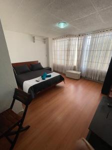 ein Schlafzimmer mit einem Bett sowie Holzböden und -fenster in der Unterkunft Apt est castellana cll 97 in Bogotá